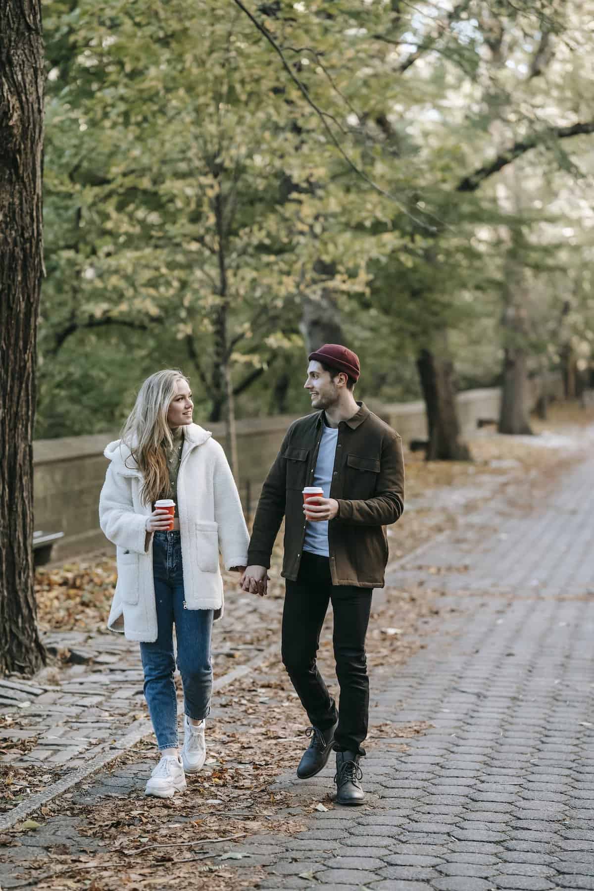 8 TIPS TO STAY HEALTHY WHILE TRAVELING: SIMPLE & ON-THE-GO 9 Young couple strolling and chatting in park with coffee cups