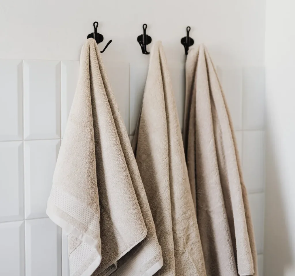 39 VALUABLE ADU IDEAS TO OPTIMIZE SPACE IN A BACKYARD BUILD (700+ PICS) 224 Beige hand towel and face towel and floor towel hooked in bathroom against white tiles in hotel room
