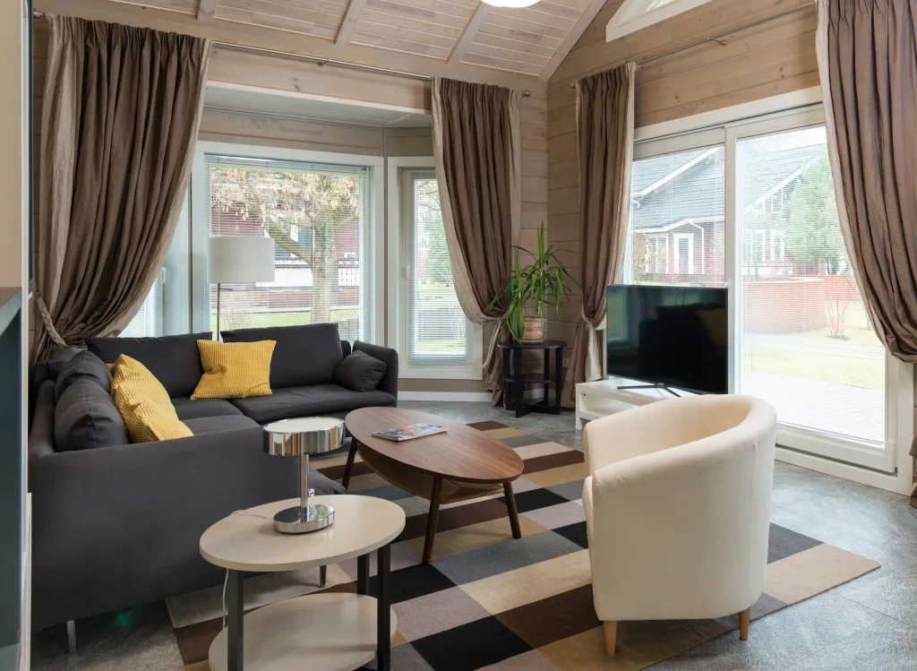 39 VALUABLE ADU IDEAS TO OPTIMIZE SPACE IN A BACKYARD BUILD (700+ PICS) 113 Comfortable corner sofa with cushions placed near round wooden table and armchair in living room equipped with TV set