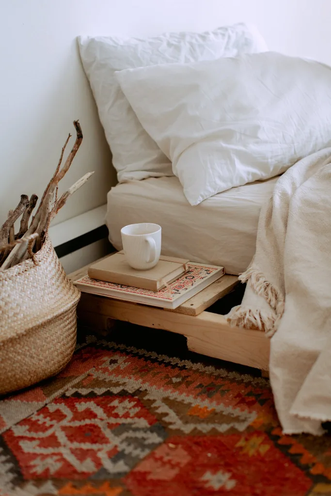 WHAT IS A TINY HOUSE? THE AFFORDABLE HOUSING OPTION EXPLAINED IN 2024 34 Comfortable cozy bedroom with bed wooden shelves with book and cup while wicker basket with sticks placed on ethnic styled rug