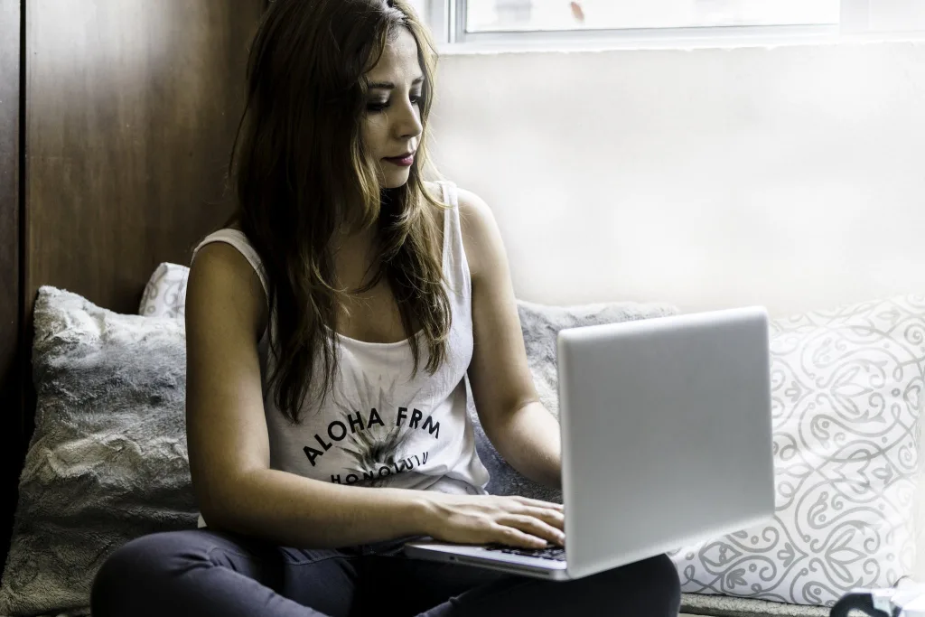 39 VALUABLE ADU IDEAS TO OPTIMIZE SPACE IN A BACKYARD BUILD (700+ PICS) 63 Woman Sitting on Couch With Macbook Pro on Lap