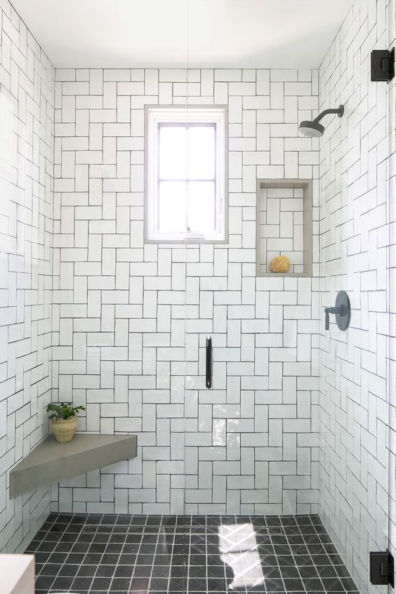 21 STUNNING SHOWER TILE IDEAS FOR SMALL BATHROOMS 13 A built-in shelf, a gray bench, black fixtures, white subway patterned tiles tiles, and dark grout adorn this compact, light-filled shower.