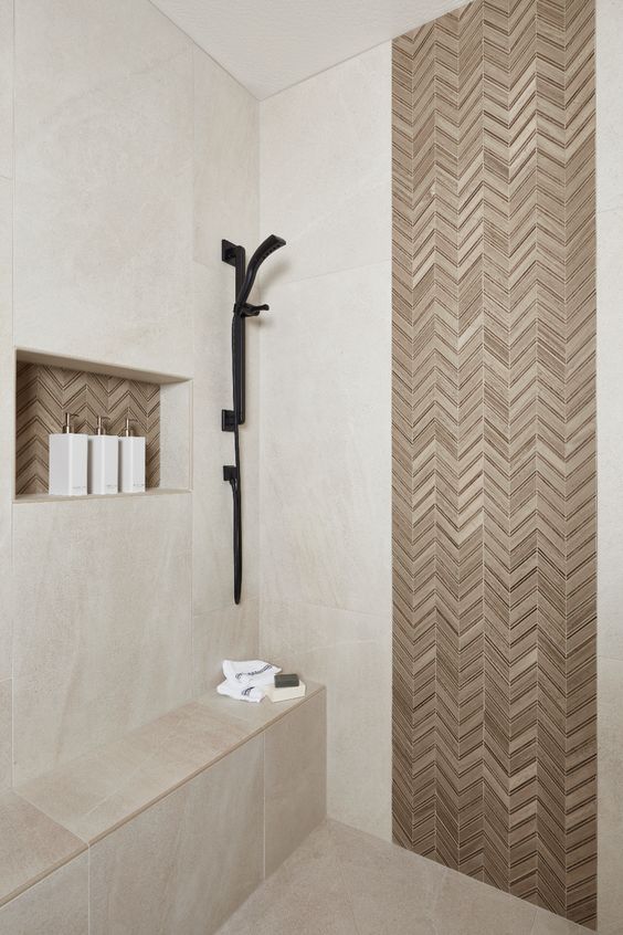 21 STUNNING SHOWER TILE IDEAS FOR SMALL BATHROOMS 11 a simple tiny shower design with walls that are sandy beige, a built-in shelf, sleek black fixtures, and an accent strip of neutral tone tiles.