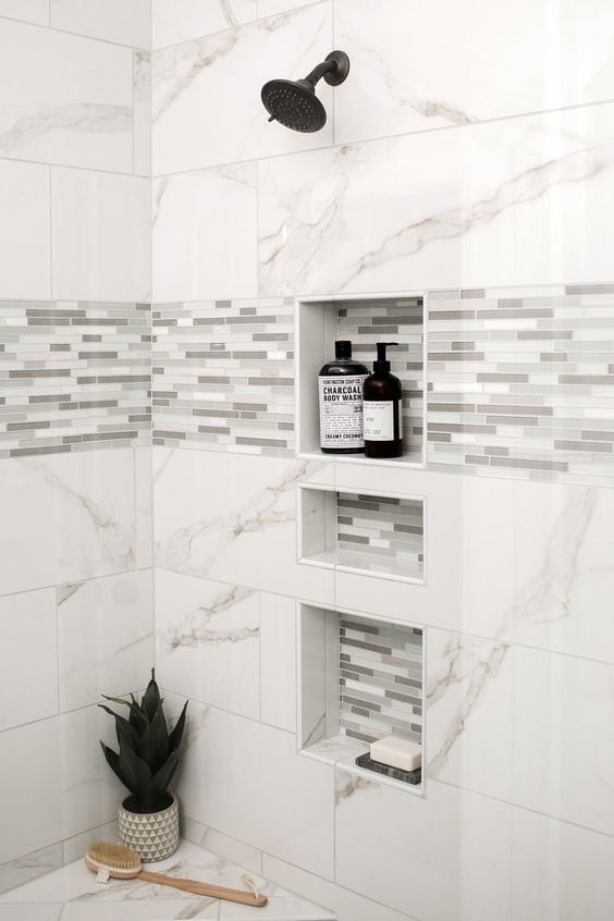 21 STUNNING SHOWER TILE IDEAS FOR SMALL BATHROOMS 14 Small contemporary shower with black shower fittings, a built-in niche with mosaic accents, and white bordered accent tiles.