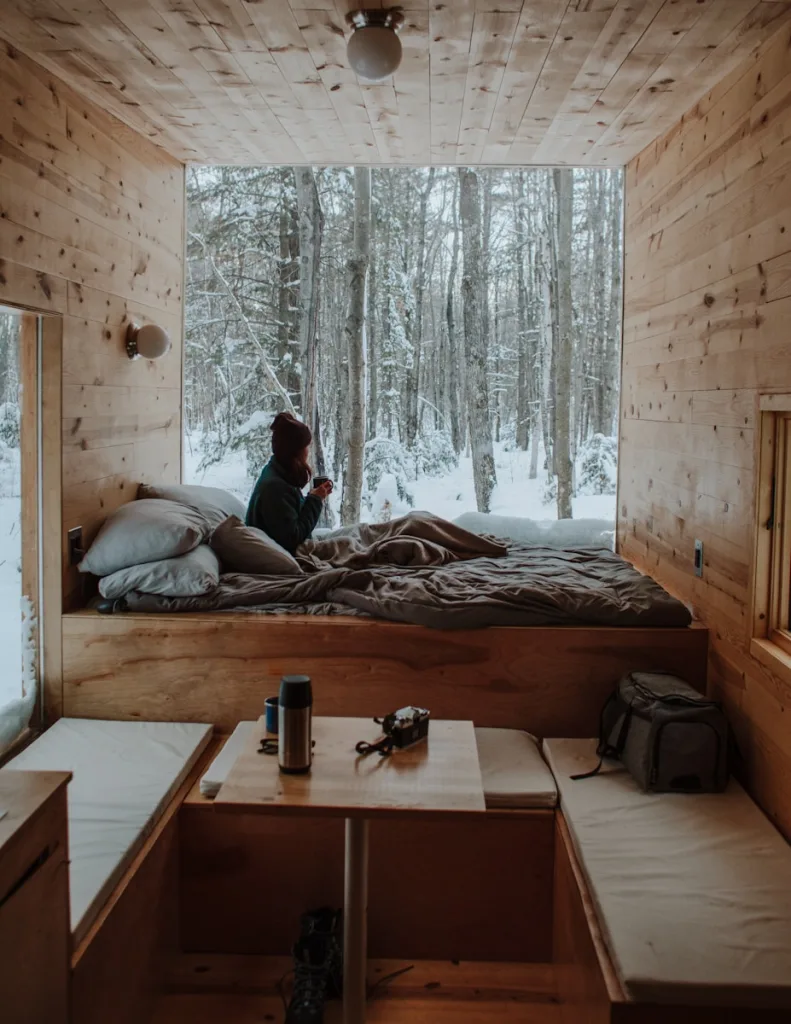 69 TINY HOUSE QUOTES: LIVING LARGE IN SMALL SPACES 1 woman sitting on bed watching by the window during winter