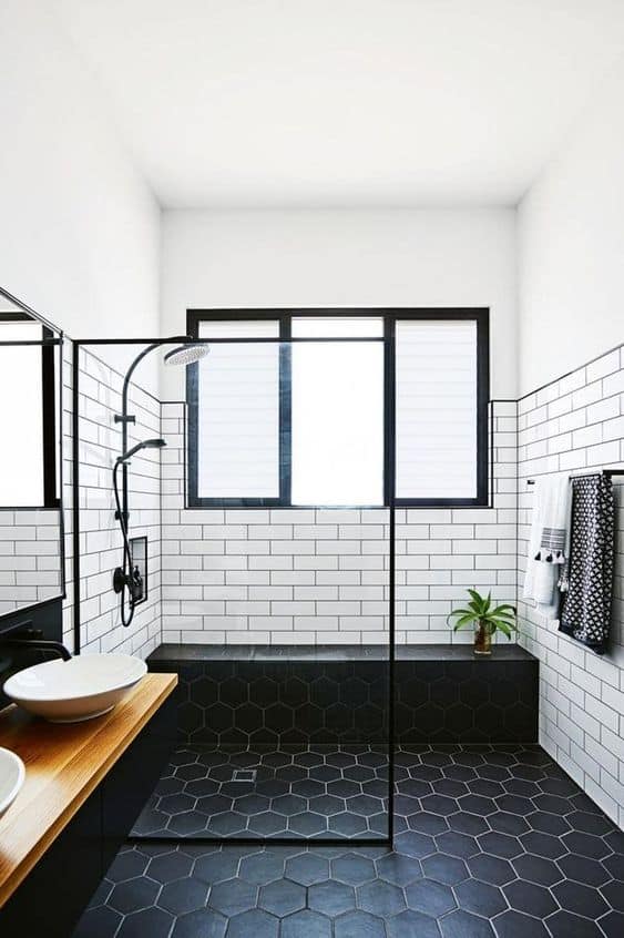 21 STUNNING SHOWER TILE IDEAS FOR SMALL BATHROOMS 17 A bright tiny bathroom with contrasting grout white subway tiles and dark hexagonal floor tiles, black framed glass shower, and a sleek wooden vanity.