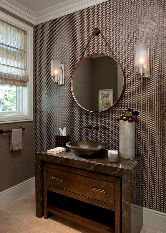 21 STUNNING SHOWER TILE IDEAS FOR SMALL BATHROOMS 6 A chic bathroom with a marbled vanity, round mirror, and walls clad in small brown penny tiles complemented by sconce lighting.