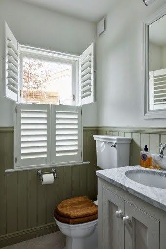 18 SMALL BATHROOM WINDOW IDEAS FOR NATURAL LIGHT AND PRIVACY 5 Traditional toilet area with olive green lower wall paneling, louvered window shutters, and a built-in washbasin with granite countertop.