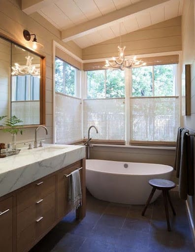18 SMALL BATHROOM WINDOW IDEAS FOR NATURAL LIGHT AND PRIVACY 7 Classic bathroom with a touch of elegance, highlighted by a pedestal sink, an ornate mirror, and a Top Down-Bottom Up Shades with sheer drapes allowing soft light.