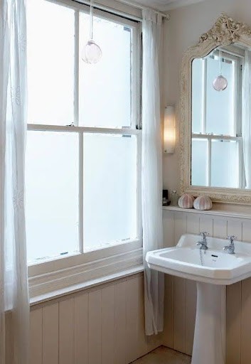 18 SMALL BATHROOM WINDOW IDEAS FOR NATURAL LIGHT AND PRIVACY 9 Classic bathroom with a touch of elegance, highlighted by a pedestal sink, an ornate mirror, and a large window film with sheer drapes allowing soft light.