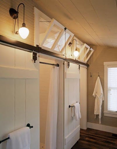 18 SMALL BATHROOM WINDOW IDEAS FOR NATURAL LIGHT AND PRIVACY 16 Rustic bathroom with a unique overhead track supporting three small, Transom windows, which infuse the space with natural light.