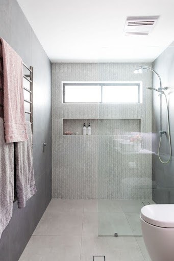 18 SMALL BATHROOM WINDOW IDEAS FOR NATURAL LIGHT AND PRIVACY 19 Minimalist bathroom showcasing a Slim Horizontal Windows above a walk-in shower, set against mosaic tiled walls in muted tones.