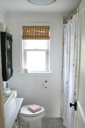 18 SMALL BATHROOM WINDOW IDEAS FOR NATURAL LIGHT AND PRIVACY 22 Compact bathroom with a bamboo roller blind over a small frosted window, complementing the black-framed shower and white wall tiles.