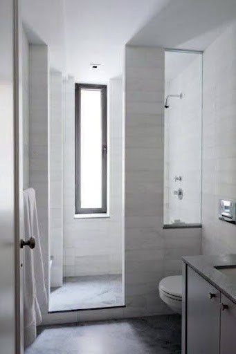 18 SMALL BATHROOM WINDOW IDEAS FOR NATURAL LIGHT AND PRIVACY 24 Sidelight Windows illuminating a modern bathroom, with white marble tiles and a glass-walled shower area.