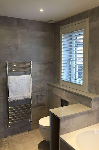 18 SMALL BATHROOM WINDOW IDEAS FOR NATURAL LIGHT AND PRIVACY 25 Contemporary bathroom featuring a Wooden Shutters window, which provides both natural light and privacy, set against a wall of large grey tiles.