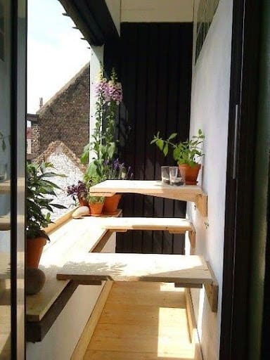 20 SMALL PATIO FURNITURE IDEAS TO MAKE A BIG IMPACT 13 A creatively designed small-space balcony Folding Bench, doubling as a plant stand, maximizing the area with practicality and rustic charm.
