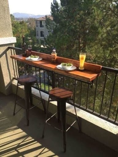 20 SMALL PATIO FURNITURE IDEAS TO MAKE A BIG IMPACT 18 A narrow balcony rail-mounted table and stool set, making the most of a small area to enjoy meals with a view in an apartment setting.