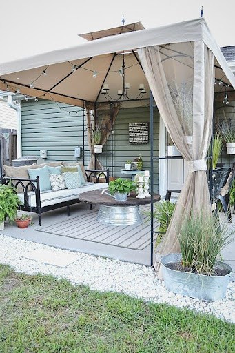 20 SMALL PATIO FURNITURE IDEAS TO MAKE A BIG IMPACT 26 An elegant patio draped with sheer curtains and featuring a gazebo-style canopy, with chic outdoor furnishings centered around a metal fire pit.