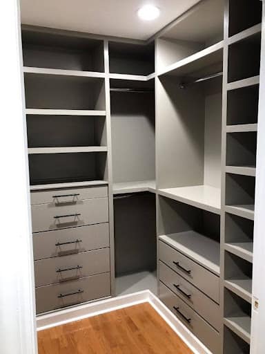 22 AWESOME SMALL WALK-IN CLOSET IDEAS FOR TINY HOMES & ADUS 8 A small corner closet setup with gray shelving units and multiple drawers for organized storage.