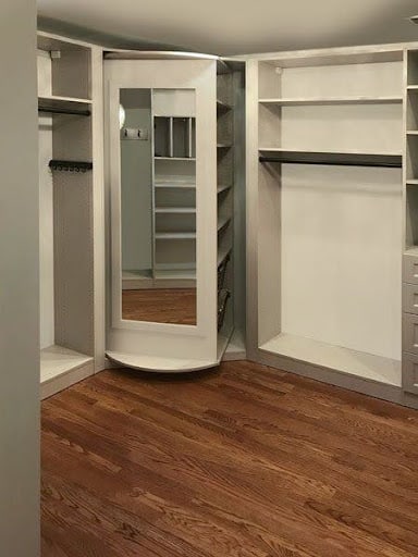 22 AWESOME SMALL WALK-IN CLOSET IDEAS FOR TINY HOMES & ADUS 12 A curved corner mirror reflecting a small, efficiently organized closet space.