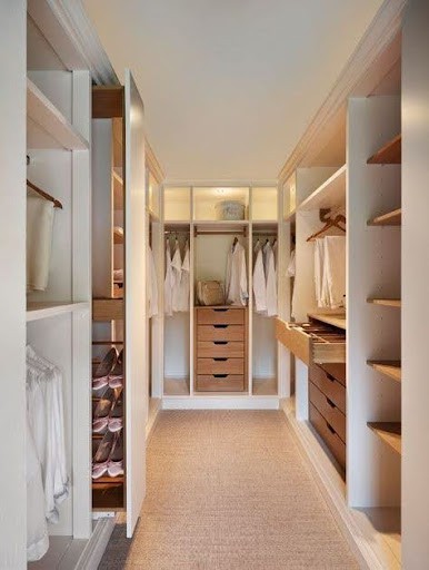22 AWESOME SMALL WALK-IN CLOSET IDEAS FOR TINY HOMES & ADUS 22 A long walk-in closet with classic wood shelving on either side, leading to a lit space with drawers and hanging areas.
