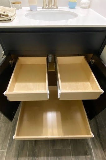 TOWEL STORAGE FOR A SMALL BATHROOM: 19 CREATIVE SOLUTIONS 9 Open vanity drawers showcasing potential hidden towel storage areas in a small bathroom space.