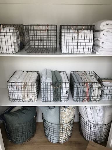 TOWEL STORAGE FOR A SMALL BATHROOM: 19 CREATIVE SOLUTIONS 13 Assorted towels organized in wire baskets on shelves, maximizing storage in a small bathroom.