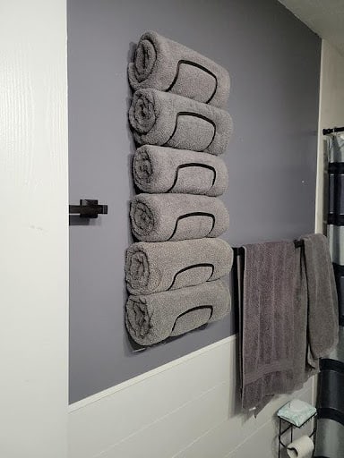 TOWEL STORAGE FOR A SMALL BATHROOM: 19 CREATIVE SOLUTIONS 16 Grey towels rolled and mounted on a wall rack, a space-efficient towel storage idea for small bathrooms