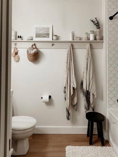 TOWEL STORAGE FOR A SMALL BATHROOM: 19 CREATIVE SOLUTIONS 18 A cozy bathroom with towels hanging below a shelf with hooks, showing simple and accessible towel storage for a small bathroom.