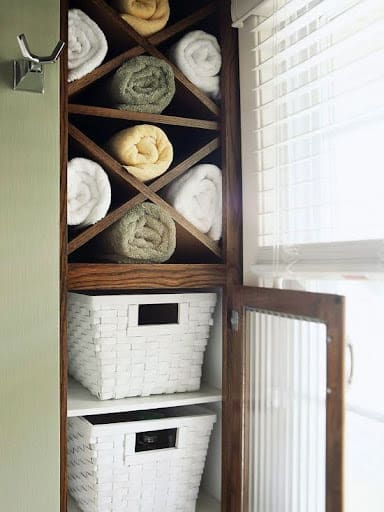 TOWEL STORAGE FOR A SMALL BATHROOM: 19 CREATIVE SOLUTIONS 21 Towels rolled in a Vertical Towel Storage Cabinet: and baskets in a bathroom cabinet, a creative towel storage idea in a small space.