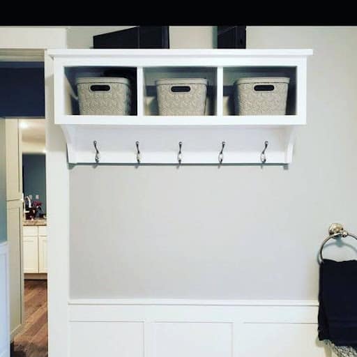 TOWEL STORAGE FOR A SMALL BATHROOM: 19 CREATIVE SOLUTIONS 24 A white shelf with hooks and gray storage baskets overhead, a functional towel storage system for tight bathroom spaces.