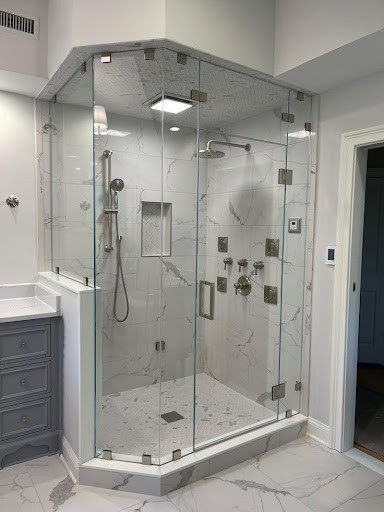 21 SMALL BATHROOM SHOWER IDEAS PERFECT FOR TINY HOUSES & ADUS 2 A Frameless Glass Enclosure corner shower in this small bathroom showcases marble-look tiles that create a luxurious atmosphere, enhanced by the sophisticated grey vanity unit beside it.
