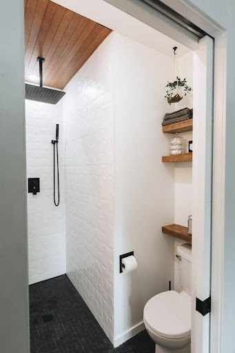 21 SMALL BATHROOM SHOWER IDEAS PERFECT FOR TINY HOUSES & ADUS 9 Cozy Compact Fixtures small bathroom shower with wooden accents, white subway tiles, and black hardware, exuding rustic charm.