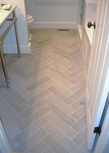 19 SMALL BATHROOM FLOOR TILE IDEAS: ADDING PERSONALITY TO A TINY HOUSE 2 Light gray herringbone pattern floor tiles lead into a white tiny bathroom, offering a sleek and elegant linear flow.