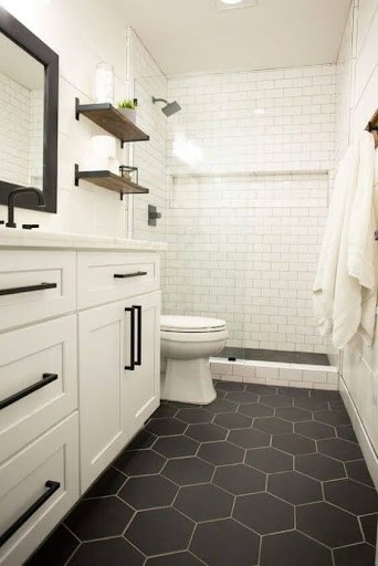 19 SMALL BATHROOM FLOOR TILE IDEAS: ADDING PERSONALITY TO A TINY HOUSE 3 Small bathroom with black hexagon floor tiles, white subway wall tiles, wood floating shelves, and white cabinetry for a modern monochrome look.