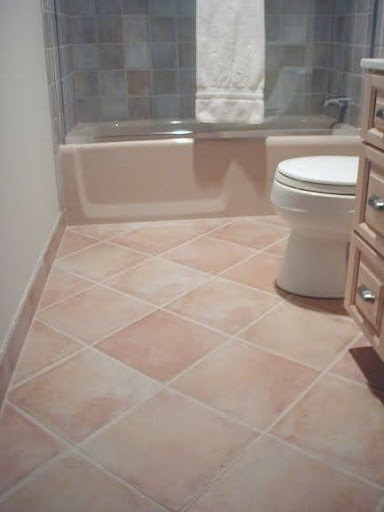 19 SMALL BATHROOM FLOOR TILE IDEAS: ADDING PERSONALITY TO A TINY HOUSE 4 Peach-toned square floor tiles set diagonally in a small bathroom, complementing a pale bathtub and soft-hued wall tiles.
