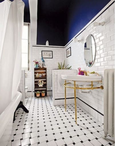 19 SMALL BATHROOM FLOOR TILE IDEAS: ADDING PERSONALITY TO A TINY HOUSE 6 A vintage-inspired small bathroom with checkered black and white Penny Tiles, white brick-patterned wall tiles, and a navy upper wall for dramatic flair.
