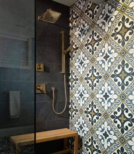 21 SMALL BATHROOM SHOWER IDEAS PERFECT FOR TINY HOUSES & ADUS 8 Tile Patterns and Colors in a small bathroom shower featuring bold patterned tiles and brass fixtures, with a wooden bench for convenience.